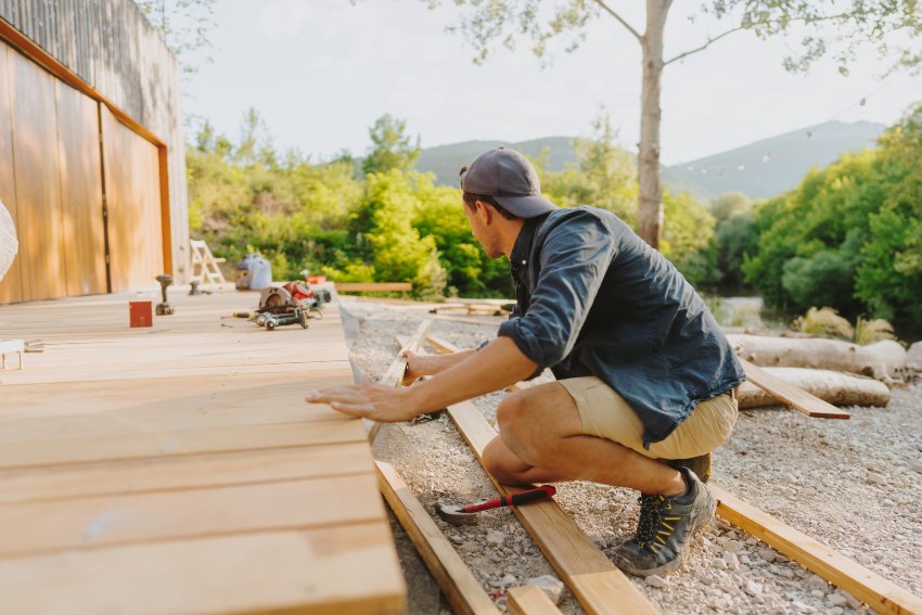 A man is engaged in deck construction outdoors using wood and tools in Salem, NH