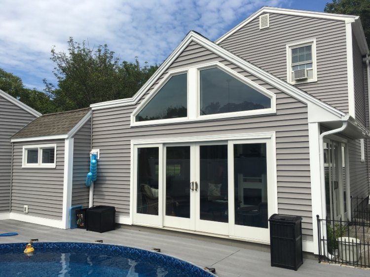 A house featuring a pool and deck, showcasing hinged patio doors installation in Salem, NH